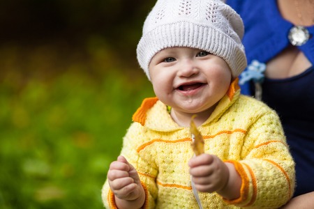 Baby child holding yellow leaf and smiling