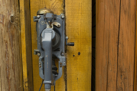 Old phone on a wooden house of yellow color