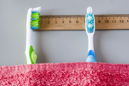 Plastic toothbrushes lie on the ruler under the towel. Shows the time to brush your teethの写真素材