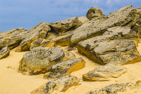 The top of one of the red sandstones with its numerous caves and visible erosion beneath the cloudy sky. Yellow sandの写真素材
