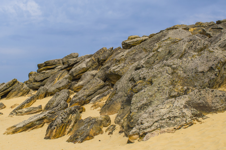 The top of one of the red sandstones with its numerous caves and visible erosion beneath the cloudy sky. Yellow sandの写真素材