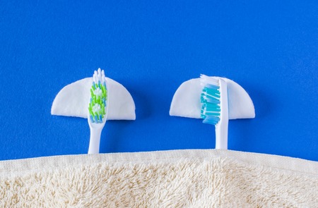 two toothbrushes lie and sleep. On pillows rest under a gray blanket. Blue backgroundの写真素材