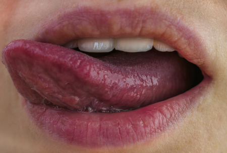 The girl shows her tongue. The girl licks her teeth with her tongueの写真素材