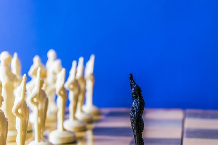 Chess on black background. The pawn is facing the enemy armyの写真素材
