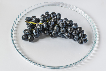 Dark grapes on a beautiful tray, on a light backgroundの写真素材