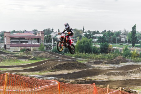 The racer on a motorcycle participates in a motocross race, jumps on a springboard. Close-up.の写真素材