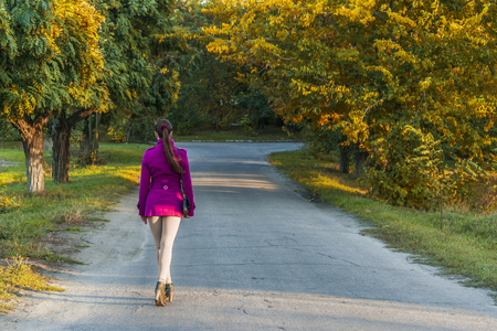 Autumn in the leaves, the girl goes into the distance along the avenue. Beautiful natureの写真素材