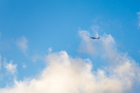 Beautiful photo of an airplane flying across a blue sky with clouds. Symbol of travel, freedom,...