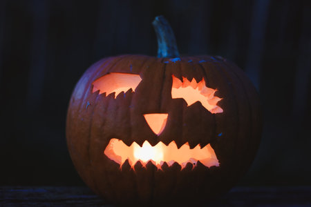 Spooky Halloween photo with carved pumpkins glowing in the dark. Festive autumn atmosphere with candle light, orange pumpkins, and seasonal decorations - perfect for holiday, Halloween, and fall themes.の写真素材