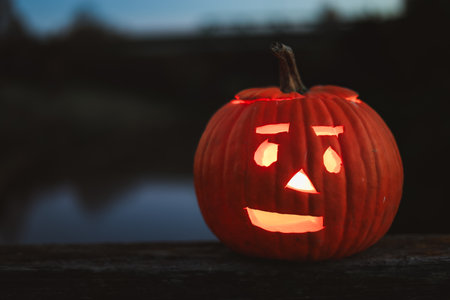 Spooky Halloween photo with carved pumpkins glowing in the dark. Festive autumn atmosphere with candle light, orange pumpkins, and seasonal decorations - perfect for holiday, Halloween, and fall themes.の写真素材
