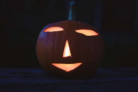 Spooky Halloween photo with carved pumpkins glowing in the dark. Festive autumn atmosphere with candle light, orange pumpkins, and seasonal decorations - perfect for holiday, Halloween, and fall themes.の写真素材