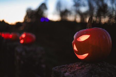 Spooky Halloween photo with carved pumpkins glowing in the dark. Festive autumn atmosphere with candle light, orange pumpkins, and seasonal decorations - perfect for holiday, Halloween, and fall themes.の写真素材