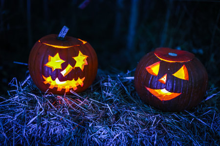 Spooky Halloween photo with carved pumpkins glowing in the dark. Festive autumn atmosphere with candle light, orange pumpkins, and seasonal decorations - perfect for holiday, Halloween, and fall themes.の写真素材