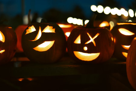 Spooky Halloween photo with carved pumpkins glowing in the dark. Festive autumn atmosphere with candle light, orange pumpkins, and seasonal decorations - perfect for holiday, Halloween, and fall themes.の写真素材