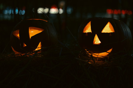 Spooky Halloween photo with carved pumpkins glowing in the dark. Festive autumn atmosphere with candle light, orange pumpkins, and seasonal decorations - perfect for holiday, Halloween, and fall themes.の写真素材