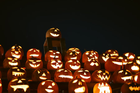 Spooky Halloween photo with carved pumpkins glowing in the dark. Festive autumn atmosphere with candle light, orange pumpkins, and seasonal decorations - perfect for holiday, Halloween, and fall themes.の写真素材