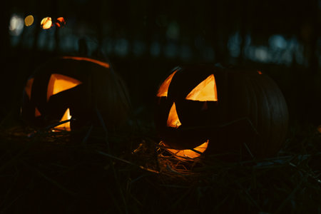 Spooky Halloween photo with carved pumpkins glowing in the dark. Festive autumn atmosphere with candle light, orange pumpkins, and seasonal decorations - perfect for holiday, Halloween, and fall themes.の写真素材