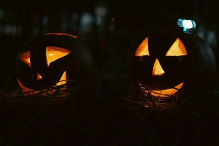 Spooky Halloween photo with carved pumpkins glowing in the dark. Festive autumn atmosphere with candle light, orange pumpkins, and seasonal decorations - perfect for holiday, Halloween, and fall themes.の写真素材