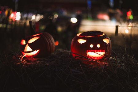 Spooky Halloween photo with carved pumpkins glowing in the dark. Festive autumn atmosphere with candle light, orange pumpkins, and seasonal decorations - perfect for holiday, Halloween, and fall themes.の写真素材