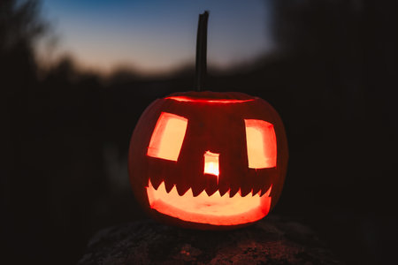 Spooky Halloween photo with carved pumpkins glowing in the dark. Festive autumn atmosphere with candle light, orange pumpkins, and seasonal decorations - perfect for holiday, Halloween, and fall themes.の写真素材