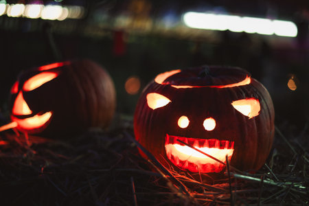 Spooky Halloween photo with carved pumpkins glowing in the dark. Festive autumn atmosphere with candle light, orange pumpkins, and seasonal decorations - perfect for holiday, Halloween, and fall themes.の写真素材