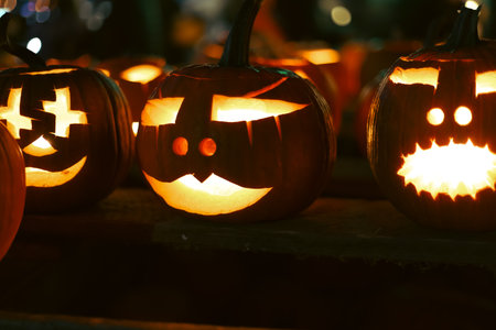 Spooky Halloween photo with carved pumpkins glowing in the dark. Festive autumn atmosphere with candle light, orange pumpkins, and seasonal decorations - perfect for holiday, Halloween, and fall themes.の写真素材