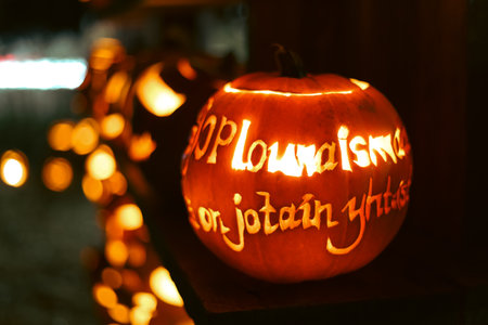 Spooky Halloween photo with carved pumpkins glowing in the dark. Festive autumn atmosphere with candle light, orange pumpkins, and seasonal decorations - perfect for holiday, Halloween, and fall themes.の写真素材
