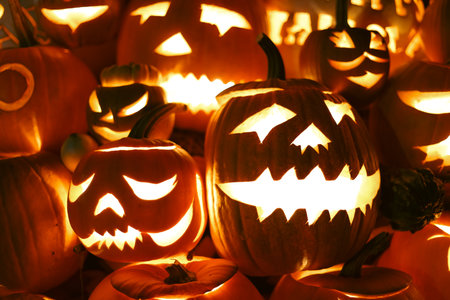 Spooky Halloween photo with carved pumpkins glowing in the dark. Festive autumn atmosphere with candle light, orange pumpkins, and seasonal decorations - perfect for holiday, Halloween, and fall themes.の写真素材