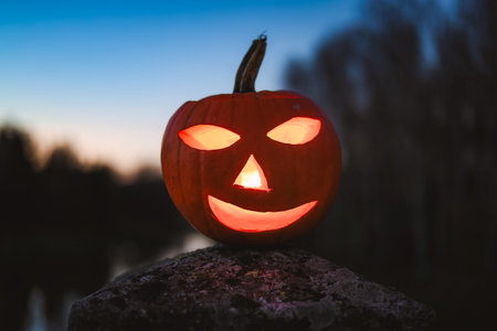 Spooky Halloween photo with carved pumpkins glowing in the dark. Festive autumn atmosphere with candle light, orange pumpkins, and seasonal decorations - perfect for holiday, Halloween, and fall themes.の写真素材