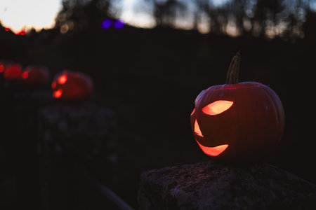 Spooky Halloween photo with carved pumpkins glowing in the dark. Festive autumn atmosphere with candle light, orange pumpkins, and seasonal decorations - perfect for holiday, Halloween, and fall themes.の写真素材