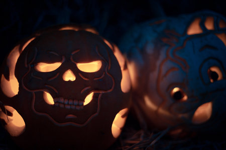 Halloween. Carved Halloween pumpkins glowing with candlelight inside at night, spooky and festive atmosphere with dark background.の写真素材