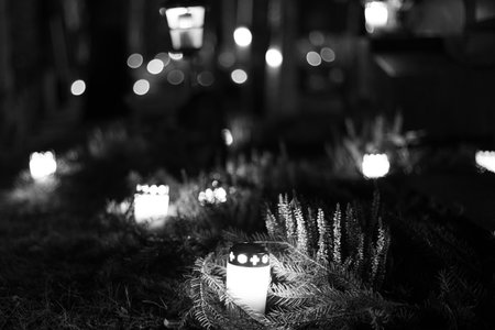Black and white photograph of cemetery crosses and glowing lanterns, soft candlelight creating a deep emotional and spiritual atmosphere. The monochrome style emphasizes contrast, symbolism and the quiet mood of remembrance.の写真素材