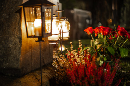Lit candles on a cemetery at night, warming flames creating a calm and emotional memorial atmosphere among graves.の写真素材