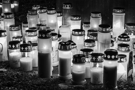 Black and white photograph of cemetery crosses and glowing lanterns, soft candlelight creating a deep emotional and spiritual atmosphere. The monochrome style emphasizes contrast, symbolism and the quiet mood of remembrance.の写真素材