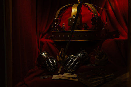 Medieval crown, sword, and an old letter arranged on a wooden table, creating a royal and historical scene with dramatic antique textures.の写真素材
