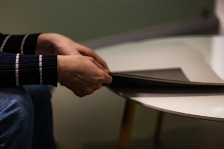 Close-up photograph of human hands flipping through a magazine. Clear details of the paper, texture, and page movement. Perfect for lifestyle imagery, education, reading habits, print media, and editorial themes.の写真素材