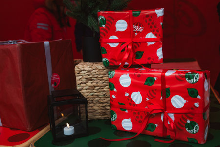 Photo of beautifully wrapped Coca-Cola-style Christmas presents with red festive paper and ribbons. Captured with warm ambient lighting to enhance the cozy holiday atmosphere.のeditorial素材