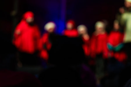 Photo of children performing on stage during a New Year concert, singing under festive lights and...