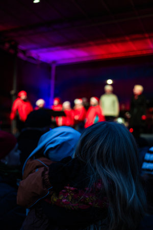 Photo of children performing on stage during a New Year concert, singing under festive lights and holiday decorations.の写真素材
