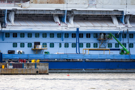 Photo of a large ship being constructed at a shipyard near the sea, captured from a distant vantage...