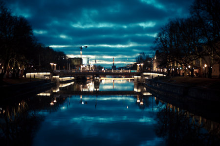 Photo of a night city located along a river, with bright city lights reflecting on the water surface. The image captures an atmospheric night urban scene, ideal for travel, architecture, cityscape, and modern lifestyle themes.の写真素材