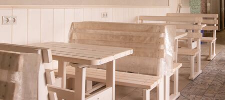 wooden tables and benches stand in a row against the wallの写真素材
