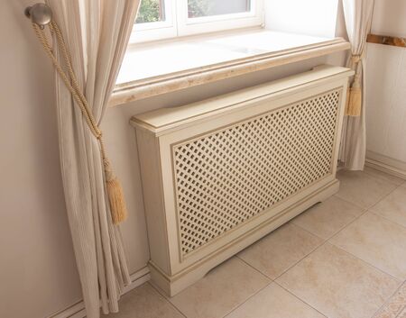 the heating radiator is fixed to the wall under the windowの写真素材