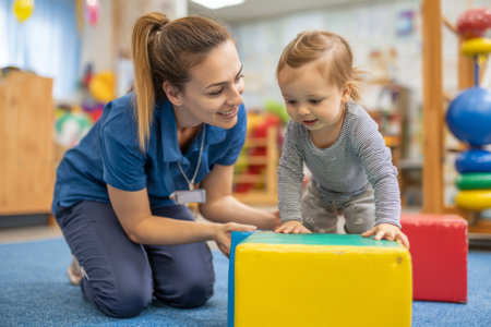 A young child enjoys stacking blocks on a carpet while an attentive adults encourages play in a cheerfulの素材