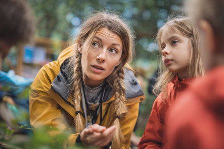 Children gather around a knowledgeable instructor in a vibrant forest, eagerly learning about nature and engaging in hands-on exploration. The scene is lively and educational.の素材