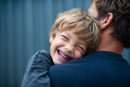 A young boy smiles brightly while hugging his parent from behind. They are outside, enjoying a warm, sunny day together. The atmosphere feels loving and carefree.の素材