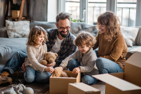 In a warm and inviting living room, a family enjoys unpacking a box filled with stuffed toys. Two children eagerly explore the contents, sharing happy moments with their parents.の素材