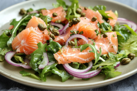 A delicious chilled smoked salmon salad is beautifully arranged with tender mixed greens, tangy capers, and thinly sliced red onions, creating a refreshing dish perfect for any meal.の素材