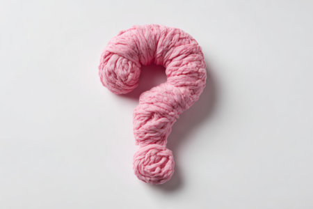 A pink question mark made of soft fabric is placed on a plain white background. This object is clearly visible and highlights curiosity and inquiry in any artistic or design context.の素材