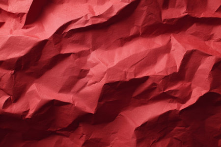 A piece of red paper shows slight creases and folds. The focus is on the texture and color of the paper, providing an interesting visual element.の素材